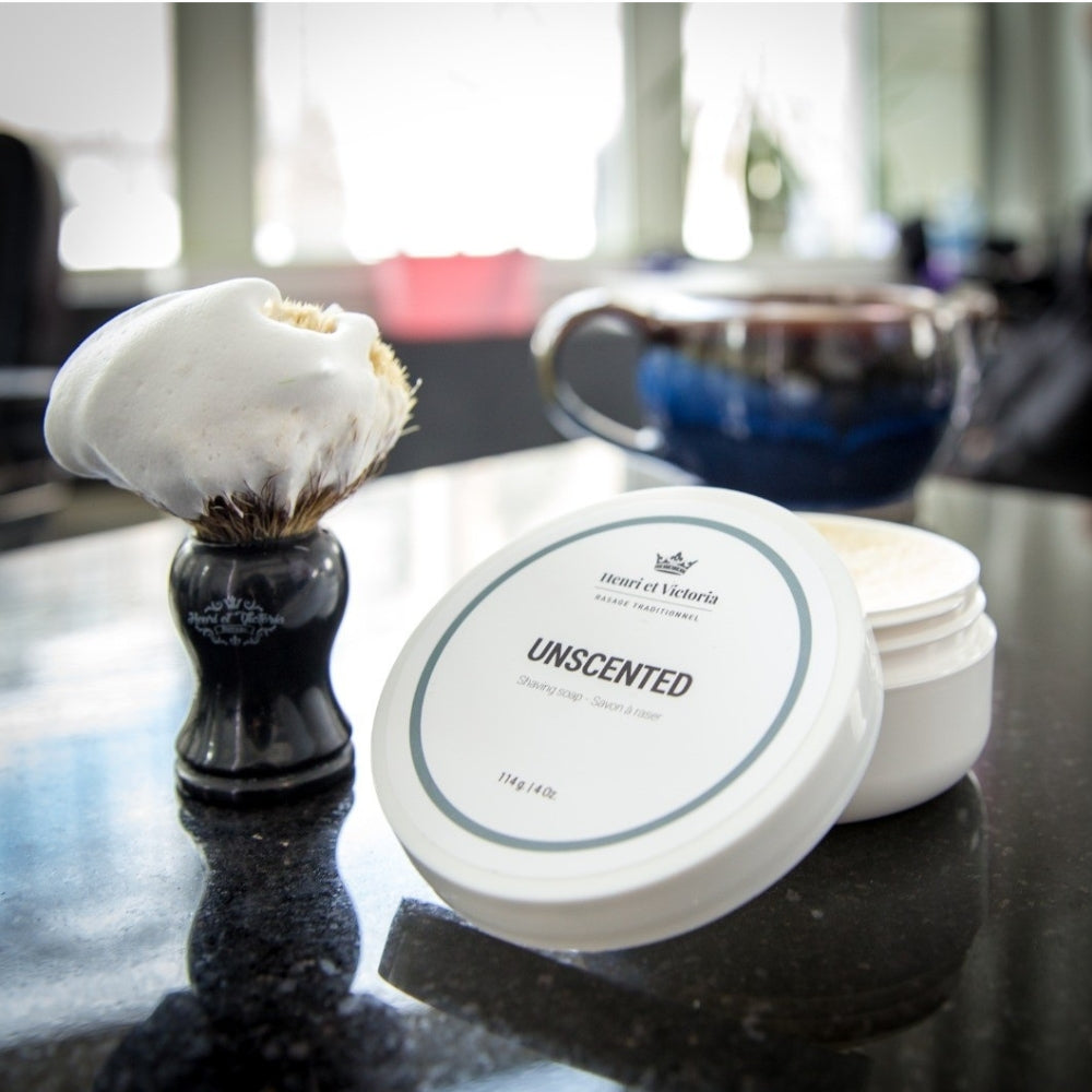 Brosse à raser avec mousse et savon à raser non parfumé posé sur un comptoir de salle de bain
